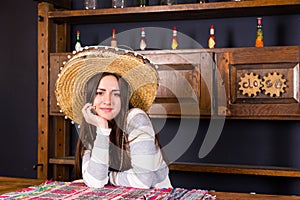 Beautiful young woman in a sombrero leaned on bar counter in a p