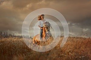 Beautiful  young woman on spanish buckskin horse in rue field