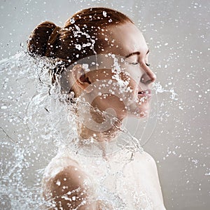 Beautiful young woman in splashes of clear water.