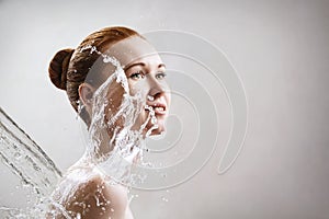 Beautiful young woman in splashes of clear water.