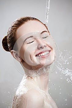 Beautiful young woman in splashes of clear water.