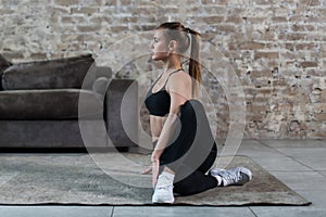 Beautiful young woman in sportswear doing seated spinal twist practicing yoga in living room