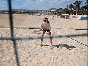 Beautiful young woman is standing at the beach volleyball court