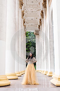 Beautiful young woman is standing between the columns