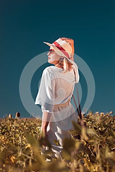 Beautiful young woman standing in field in summer