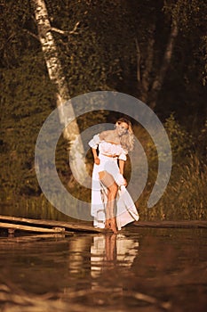 Beautiful young woman standing by the lake showing her legs