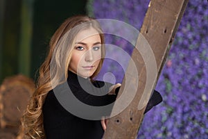 Beautiful young woman standing, leaning on the ladder. indoor. L