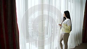 Beautiful young woman standing looking window