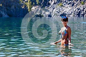 Beautiful young woman standing in a mountain lake