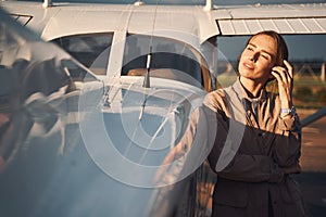 Beautiful young woman standing near aircraft at airdrome