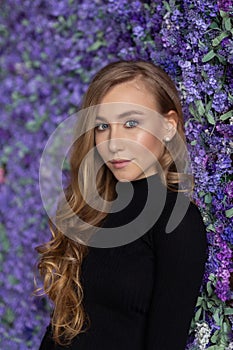 Beautiful young woman standing near flowers wall. indoor. Looking in camera. Beautiful face. Selective focus. Close-up portrait.