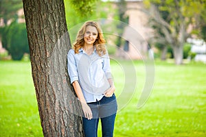 Beautiful young woman standing next to a tree