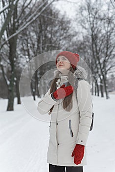 Beautiful young woman standing among the snowy trees in the winter forest. Vertical frame