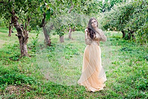 Beautiful young woman is standing between the trees