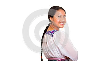 Beautiful young woman standing wearing traditional andean blouse and red necklace, turning head looking towards camera