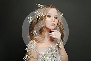 Beautiful young woman standing with white flowers. Spring. Female model with flowers in her hair in a white dress. Portrait.