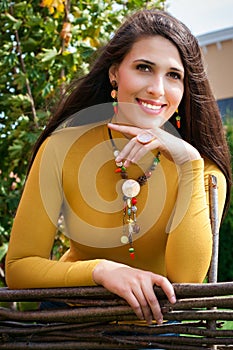 Beautiful young woman stands behind fence