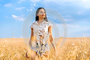 beautiful young woman stands in a wheat field with sky in background, concept freedom and tranquility