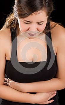 Beautiful young woman with stomach ache or nausea in a black background photo