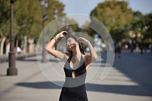 Beautiful young woman with straight brown hair, wearing an elegant black dress, touching her hair in sensual and seductive