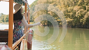 Beautiful young woman in a straw hat and dress stands and sightseening. Back view. Concept of excursions by river bus