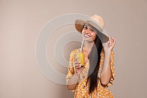Beautiful young woman with straw hat and glass of refreshing drink on beige background. Space for text