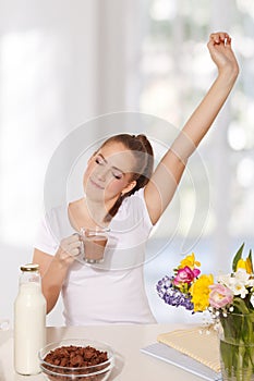 Beautiful young woman streching herself while holding a glass of