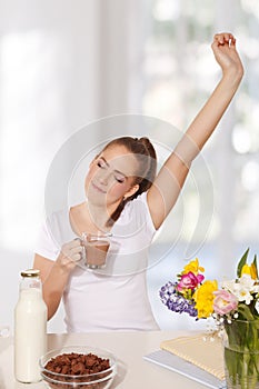 Beautiful young woman streching herself while holding a glass of photo