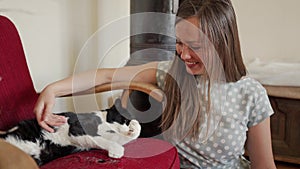 Beautiful young woman stroking cute black and white cat, close up