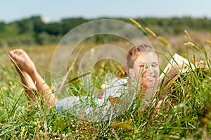 Beautiful young woman-student reading a book lying on the grass. Pretty girl outdoors in summertime