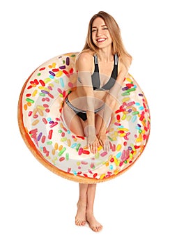Beautiful young woman in stylish bikini with doughnut inflatable ring on white