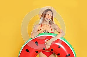 Beautiful young woman in stylish bikini with watermelon inflatable ring