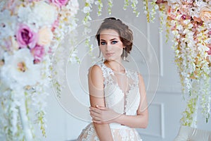 Beautiful young woman with stylish brunette hair and elegant dress posing in luxury white classic room interior with