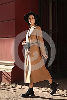 Beautiful young woman with stylish waist bag on city street