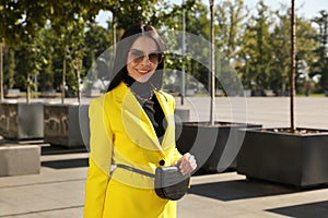 Beautiful young woman with stylish waist bag on city street