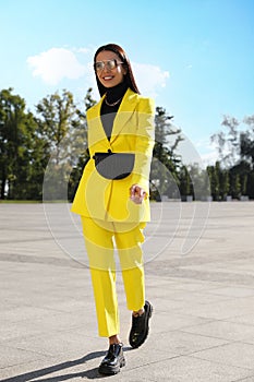 Beautiful young woman with stylish waist bag on city street