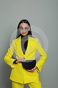 Beautiful young woman with stylish waist bag on grey background