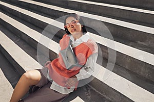 Beautiful young woman with stylish waist bag on stairs outdoors