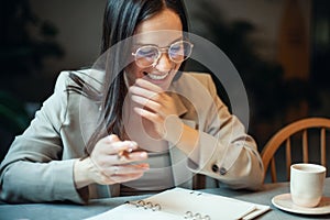 Beautiful young woman in suit writing her business plans while drinking coffee on break time