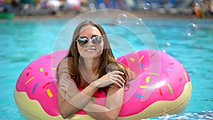 Beautiful young woman in summer. Bikini girl havin fun in in sprinkled donut float at pool, vacation, summertime, summer