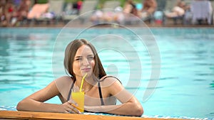 Beautiful young woman in summer. Bikini girl relaxing in tropical swimming pool. woman drinking a fresh orange