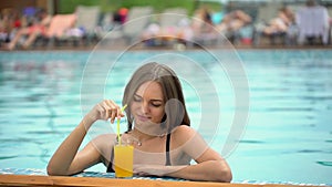 Beautiful young woman in summer. Bikini girl relaxing in tropical swimming pool. woman drinking a fresh orange