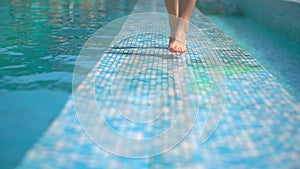 Beautiful young woman in summer. Bikini girl walking by the pool, close-up of her legs. Relaxing in tropical. The