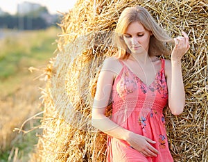 Beautiful young woman on summer dress standing in field