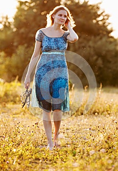 Beautiful young woman on summer dress standing in field