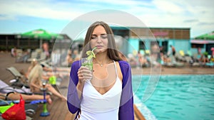 Beautiful young woman in summer. Portrait of girl near tropical pool. Luxury travel happy woman with mojito