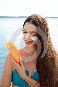 Beautiful Young woman with sun cream on face.