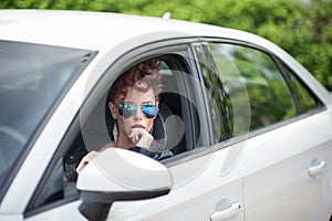 Beautiful young woman with sun glasses on looking out of the win