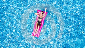 Beautiful young woman sunbathing on inflatable pink mattress at pool