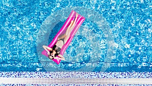 Beautiful young woman sunbathing on inflatable pink mattress at pool